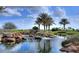 Scenic water feature with rocks and palm trees creating a tranquil atmosphere in the community at 36053 N Stoneware Dr, Queen Creek, AZ 85140