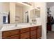 This bathroom includes double sinks with oak cabinets, a large mirror, and a walk-in closet at 42568 W Bunker Dr, Maricopa, AZ 85138