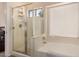 The primary bathroom features a glass shower and a built-in soaking tub under a bright window at 42568 W Bunker Dr, Maricopa, AZ 85138