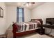This bedroom is complete with a ceiling fan, a desk, and a comfortable bed at 42568 W Bunker Dr, Maricopa, AZ 85138