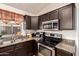 Close-up view of the kitchen area with stainless steel appliances, and dark wood cabinets at 42568 W Bunker Dr, Maricopa, AZ 85138