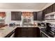 Functional kitchen space featuring granite countertops, dark wood cabinets, and modern appliances at 42568 W Bunker Dr, Maricopa, AZ 85138