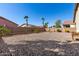 Spacious backyard featuring a gravel area, fence, and palm trees, perfect for outdoor relaxation and entertainment at 45105 W Gavilan Dr, Maricopa, AZ 85139