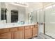 Double sink bathroom with wood cabinets, a large mirror, and a glass shower at 45105 W Gavilan Dr, Maricopa, AZ 85139