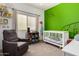 Dinosaur themed Bedroom with a white crib, green accent wall and a gray chair at 45105 W Gavilan Dr, Maricopa, AZ 85139