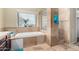 Bathroom with a soaking tub, tiled shower and window, all surrounded by travertine tile at 53 W Pecan Pl, Tempe, AZ 85284