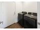This is the laundry room with black washer and dryer and access to the garage at 5719 E Santa Clara Dr, San Tan Valley, AZ 85140