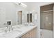 Bright bathroom featuring double sinks with sleek fixtures, a large mirror, and a shower/tub combination at 6828 E Evans Dr, Scottsdale, AZ 85254