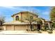 A tan stucco home has a three car garage and arched front entry, along with desert landscaping at 6828 E Evans Dr, Scottsdale, AZ 85254