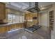 A functional kitchen with granite countertops, wood cabinets, stainless steel appliances, and a center island cooktop at 7322 E High Point Dr, Scottsdale, AZ 85266