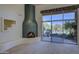 Bright living room featuring a unique fireplace, decorative display, and patio access with outdoor landscaping at 7322 E High Point Dr, Scottsdale, AZ 85266