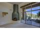A bright living room with a unique fireplace and large windows showcasing the outdoor landscape at 7322 E High Point Dr, Scottsdale, AZ 85266