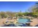 Backyard pool area with desert landscaping, cool rock features, and a pristine blue sky above at 7322 E High Point Dr, Scottsdale, AZ 85266
