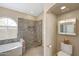 Bright bathroom featuring glass enclosed shower with decorative tile, soaking tub and fixtures at 9706 E Sheena Dr, Scottsdale, AZ 85260