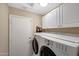 Laundry room with washer, dryer, and white cabinets for ample storage at 9706 E Sheena Dr, Scottsdale, AZ 85260