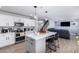 Open-concept kitchen boasts stainless appliances, white cabinetry, and an island with barstool seating at 10865 E Florian Ave, Mesa, AZ 85208