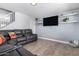Cozy living room with a leather sectional couch, floating shelves, a wall-mounted television, and wood-look tile flooring at 10865 E Florian Ave, Mesa, AZ 85208