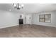 Empty living space with wood-look tile flooring, a window with blinds, and a dark cabinet at 10865 E Florian Ave, Mesa, AZ 85208