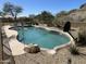 Inviting backyard pool with stone accents, desert landscaping, and a basketball hoop for recreation at 10980 E Winchcomb Dr, Scottsdale, AZ 85255