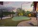 Backyard putting green with rock landscaping, pergola with seating, and charming string lights at dusk at 1422 E Royal Palm Rd, Phoenix, AZ 85020