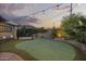 Landscaped backyard featuring a putting green, rock details, outdoor seating, and decorative string lights at 1422 E Royal Palm Rd, Phoenix, AZ 85020