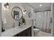 Bathroom featuring a marble countertop, undermount sink, round mirror, and tub with a tiled shower at 1422 E Royal Palm Rd, Phoenix, AZ 85020