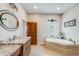 Well-lit bathroom with granite counters, wood accents, vanity, and modern tub at 15218 E San Tan Blvd, Gilbert, AZ 85298