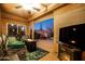 Relax on the covered patio with a fireplace, TV, and comfortable seating overlooking the backyard at 1705 W Stephanie Ln, San Tan Valley, AZ 85144