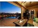 Enjoy the covered patio with outdoor fire, comfortable seating, and a view of the pool at dusk at 1705 W Stephanie Ln, San Tan Valley, AZ 85144