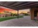 Relax under the pergola of this home, with a paved patio, lush lawn, and a charming storage shed at sunset at 21647 S 223Rd Pl, Queen Creek, AZ 85142