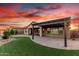 Spacious backyard with pergola-covered patio, landscaping, synthetic grass, with sunset creating a warm atmosphere at 21647 S 223Rd Pl, Queen Creek, AZ 85142