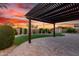 Outdoor patio with pergola, landscaping, and synthetic grass, all set against a beautiful sunset at 21647 S 223Rd Pl, Queen Creek, AZ 85142
