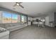 Spacious living room featuring a gray sectional, modern floors, white shutters, and a seamless flow into the kitchen at 29674 N 127Th Ln, Peoria, AZ 85383