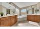 Bright bathroom featuring dual sinks, soaking tub, linen cabinets, and updated fixtures at 3005 W Donatello Dr, Phoenix, AZ 85086