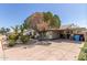 Charming home with rock landscaping, flowering bushes, palm trees, mature trees, and a covered carport at 3727 W Gardenia Ave, Phoenix, AZ 85051