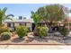 Charming home featuring rock landscaping, beautiful green shrubs, and vibrant red flowers in the well maintained front yard at 3727 W Gardenia Ave, Phoenix, AZ 85051