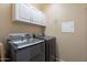Well-lit laundry room featuring modern Samsung washer and dryer and overhead cabinets for ample storage at 42711 N 43Rd Dr, New River, AZ 85087