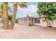 Rear exterior of the home featuring desert landscaping, palm trees, and an enclosed patio at 5022 E Magic Stone Dr, Phoenix, AZ 85044