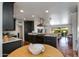 Open-concept kitchen with black cabinetry, granite countertops, a sleek vent hood, and seamless access to the dining area at 5110 E Verde Ln, Phoenix, AZ 85018