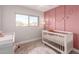 Bedroom with crib, pink accent wall, and changing table at 8807 E Dahlia Dr, Scottsdale, AZ 85260