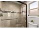 Shower with glass door, neutral tile, accent mosaic strip, chrome hardware, and corner seat at 8807 E Dahlia Dr, Scottsdale, AZ 85260