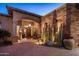 Stunning single-story home with an arched entrance, desert landscaping, and a brick driveway at dusk at 9920 E Honey Mesquite Dr # 155, Scottsdale, AZ 85262