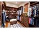 Spacious walk-in closet with custom wood shelving, drawers, and a central ottoman bench atop a patterned rug at 9920 E Honey Mesquite Dr # 155, Scottsdale, AZ 85262