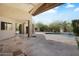 Spacious covered patio with stone tile flooring, overlooking a beautifully landscaped backyard and pool at 10290 N 117Th Pl, Scottsdale, AZ 85259