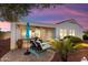 Back patio with lounge chairs, a table with umbrella, and desert landscaping under a colorful dusk sky at 12860 W Junipero Dr, Sun City West, AZ 85375