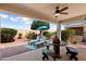 Outdoor patio featuring lounge chairs, a ceiling fan, desert landscaping and a unique table and bench set at 12860 W Junipero Dr, Sun City West, AZ 85375