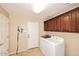 Well-lit laundry room with cabinets, tile flooring, and modern washer and dryer units at 24113 N 26Th Pl, Phoenix, AZ 85024