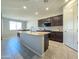 Open kitchen layout featuring an island with granite countertops, dark wood cabinets, and ample lighting at 24552 W Hilton Ave, Buckeye, AZ 85326
