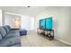 Inviting living room featuring tile flooring, a gray sofa, and a large entertainment center at 24552 W Hilton Ave, Buckeye, AZ 85326