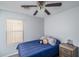 Cozy bedroom featuring a ceiling fan, window with blinds, a bed with a blue comforter and a wood bedside table at 2889 S 161St Dr, Goodyear, AZ 85338